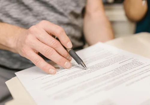 Un cliente firma un contrato junto a un sello notarial, asegurando la validez de su acta de reagrupación familiar online