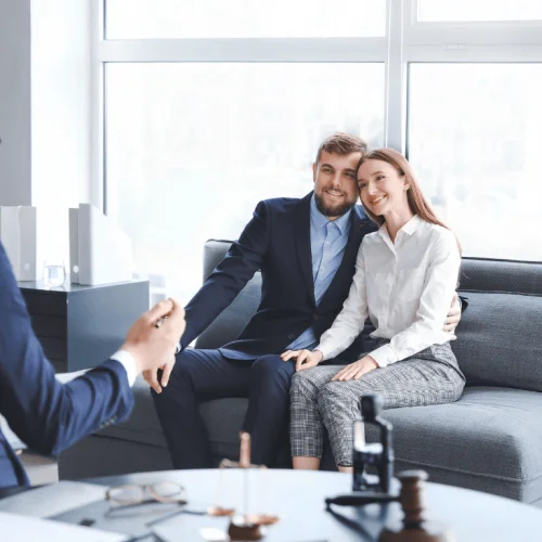 Smiling couple sitting in a lawyer's office, receiving advice on granting and revoking powers of attorney online.